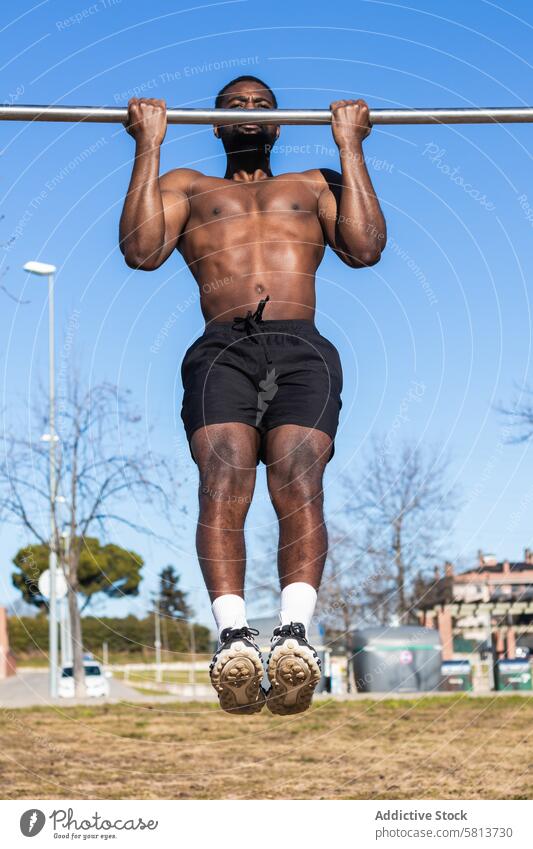 Strong black sportsman working out on bar in town pull up training workout exercise muscular strong muscle fitness sportswear african american power wellness