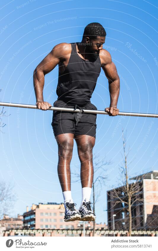 Strong black sportsman working out on bar in town pull up training workout exercise muscular strong muscle fitness sportswear african american power wellness