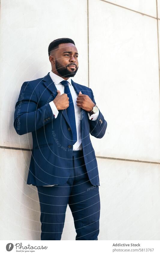 Portrait of a black business man in a suit adjusting his blazer with confidence african american male professional executive success entrepreneur finance