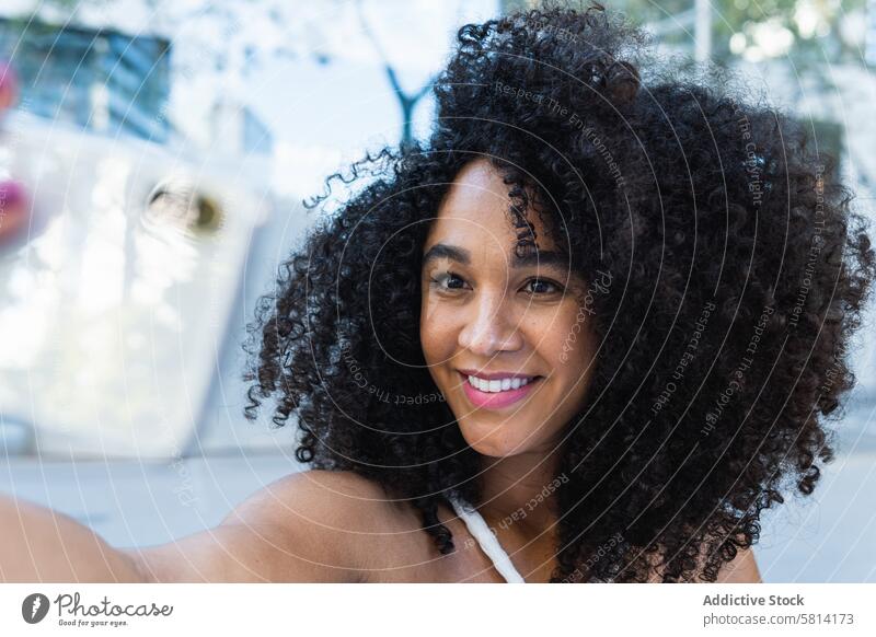 Happy black woman with curly hair reaching hand to camera positive appearance pleasant portrait carefree glee happy charming personality female delight optimist
