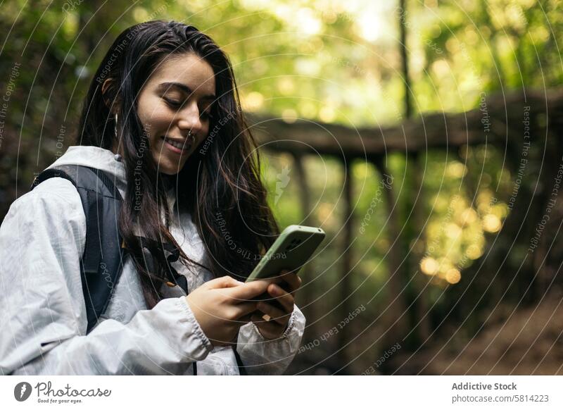 Young woman texting in the forest portrait outdoors nature lifestyle people vacation leisure looking hiking tree travel backpack autumn adventure closeup