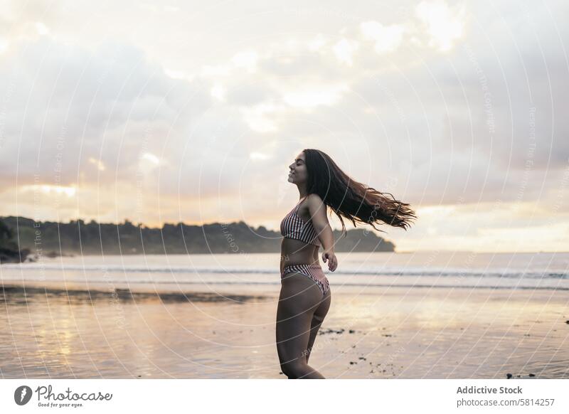 Young woman with long hair dancing on the beach sunset young sea summer lifestyle happy travel beautiful ocean nature vacation people sky female happiness