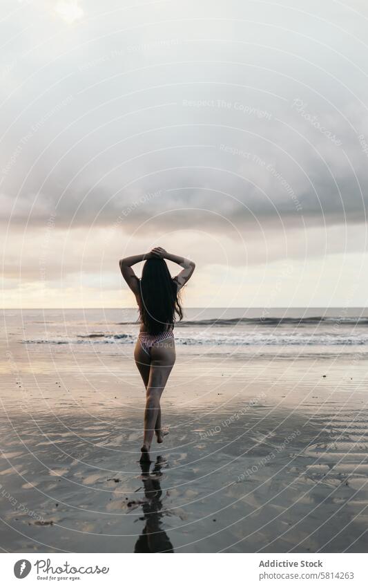 Rear view of a woman running on the beach sunset young sea summer lifestyle happy travel beautiful ocean nature vacation people sky female happiness outdoor