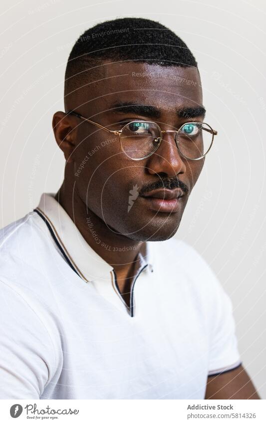 Serious black man in eyeglasses on white background serious portrait individuality confident studio shot mustache t shirt alone african american male adult