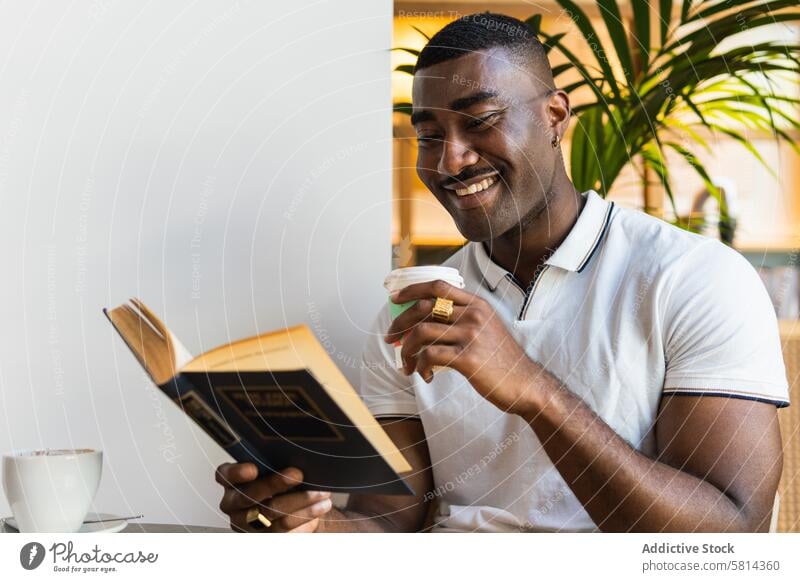 Smiling African American man reading book with drink in cafe smile paper cup alone table happy african american black male adult coffee takeaway to go hot drink