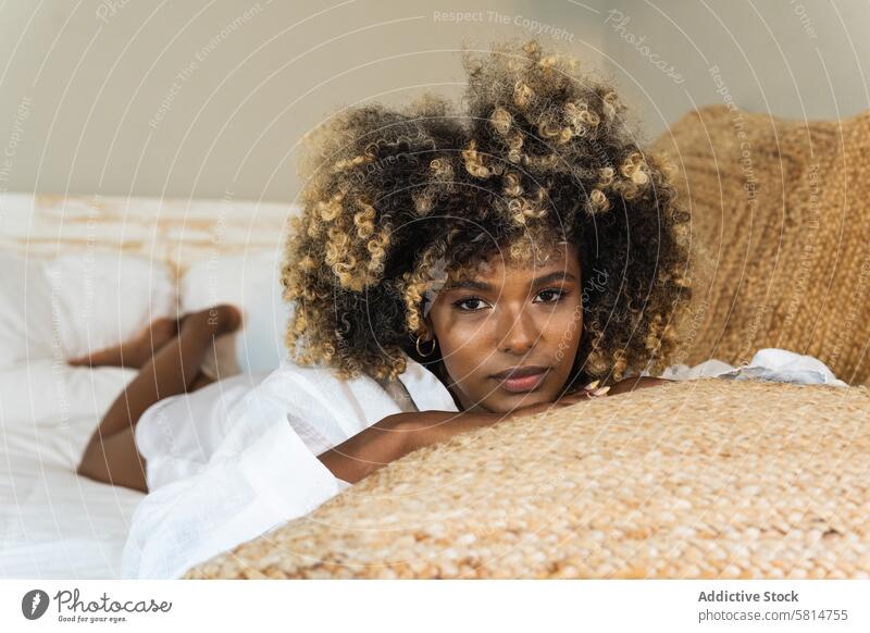 Thoughtful black woman lying on bed in bedroom enjoy rest positive comfort relax morning pleasure female happy optimist delight cheerful toothy smile home glad