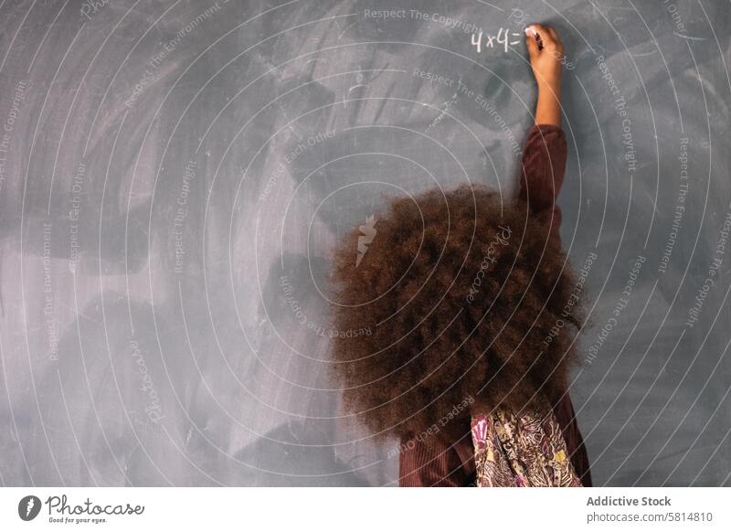 Black girl writing on chalkboard in classroom pupil mathematics example solve write lesson blackboard ethnic african american school schoolgirl study clever
