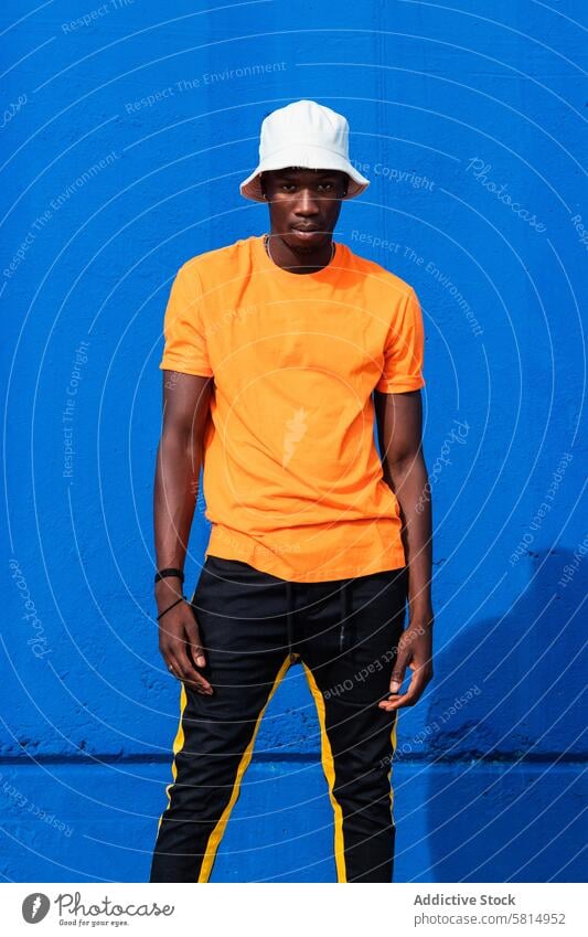 Black man in bright sporty outfit and cap posing colorful style trendy vivid modern wear male african american black ethnic confident young cool lifestyle guy