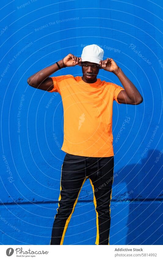 Black man in bright sporty outfit and cap colorful style trendy vivid modern wear male african american black ethnic confident young cool lifestyle guy cloth