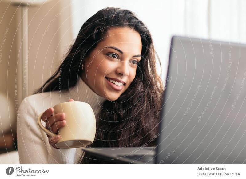 Young Woman Enjoying a Cup of Coffee While Using Laptop Sofa Home Technology Productivity Remote Connection Wireless Modern Comfort Casual Female Internet
