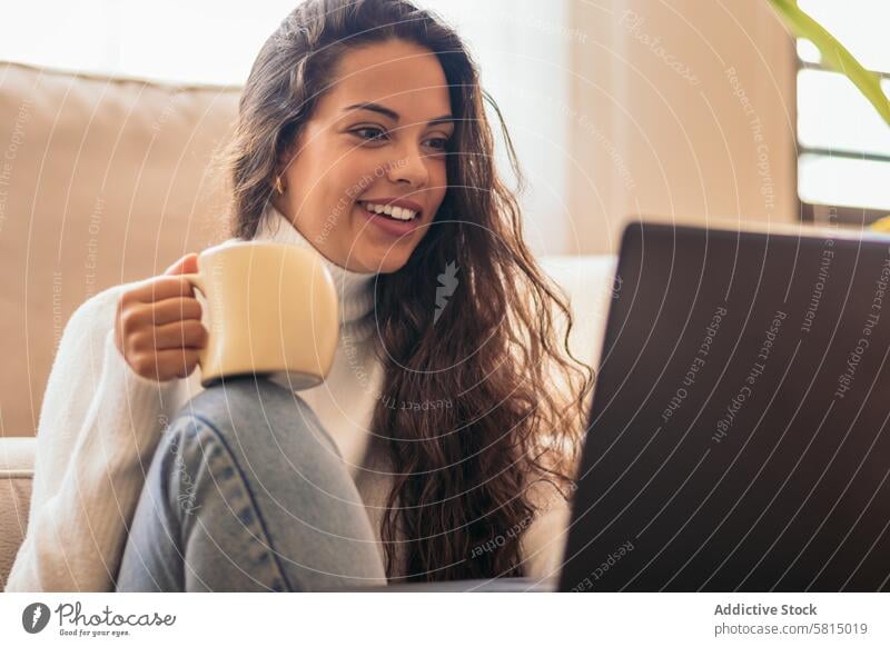 Young Woman Enjoying a Cup of Coffee While Using Laptop" Sofa Home Technology Productivity Remote Connection Wireless Modern Comfort Casual Female Internet