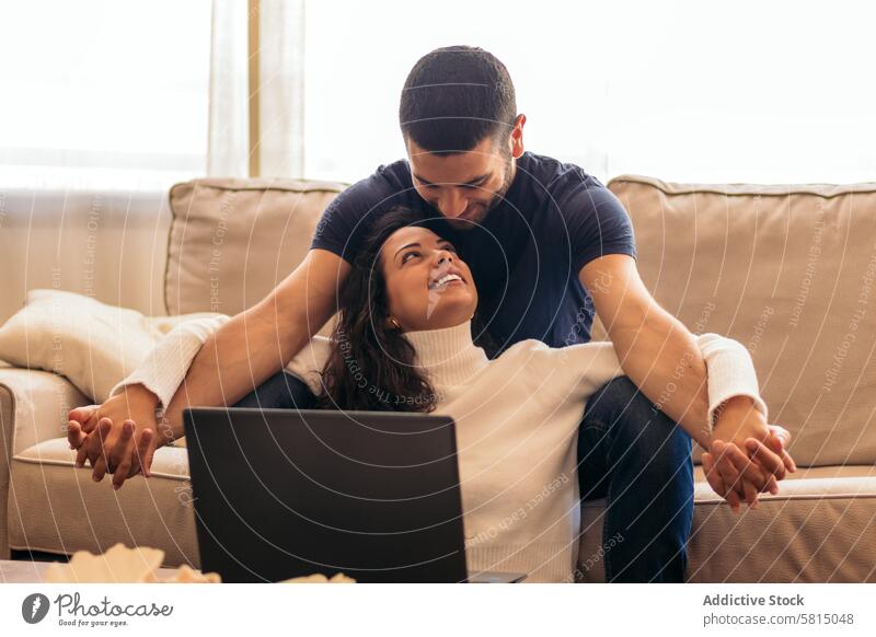 Young couple enjoying a movie on laptop at home sofa leisure relaxation technology digital streaming entertainment enjoyment cozy comfortable indoors
