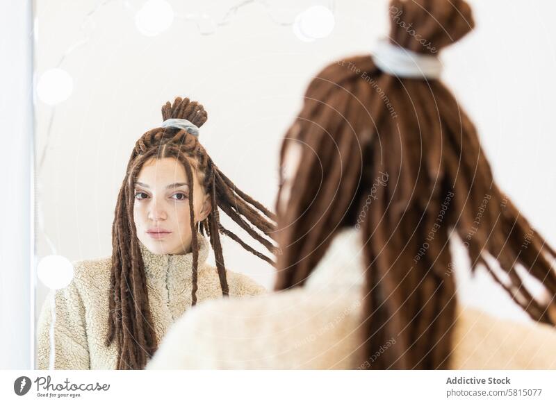 Woman with braids looking in the mirror woman female beautiful hair beauty reflection young indoors caucasian dreadlocks bathroom face person care adult skin