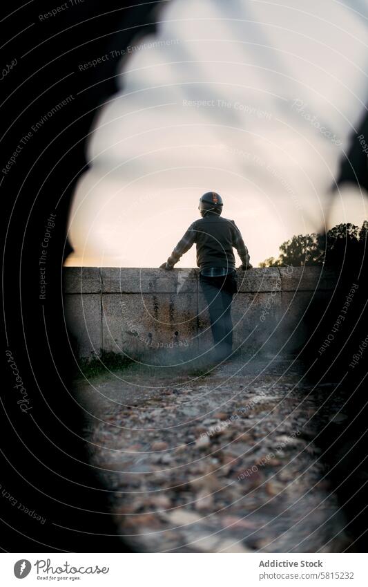 Anonymous person in helmet gazing at dusk horizon man gaze twilight contemplation adventure wall old standing individual outdoor leisure safety protective gear