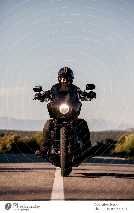 Bearded biker riding motorcycle on open road adult male beard helmet visor sunny day travel journey transportation vehicle motorbike cruiser adventure outdoor