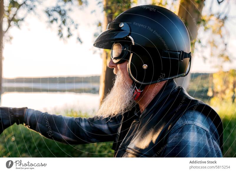 Senior Biker Looking Away While Exploring the Outdoors senior male motorcyclist helmet goggles looking away beard outdoors explorer adventure biker autumn