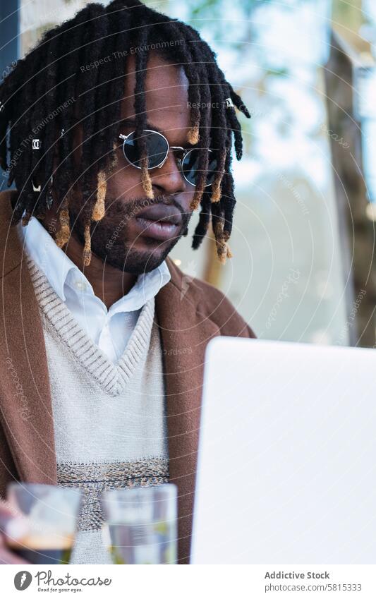Serious black man with espresso and glass of water in cafe laptop typing drink coffee street male ethnic african american browsing gadget beverage table device