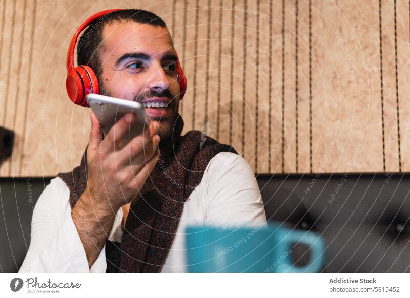 Male freelancer sending voice message businessman smile smartphone record cafe telework communicate male listen music adult device gadget headphones positive