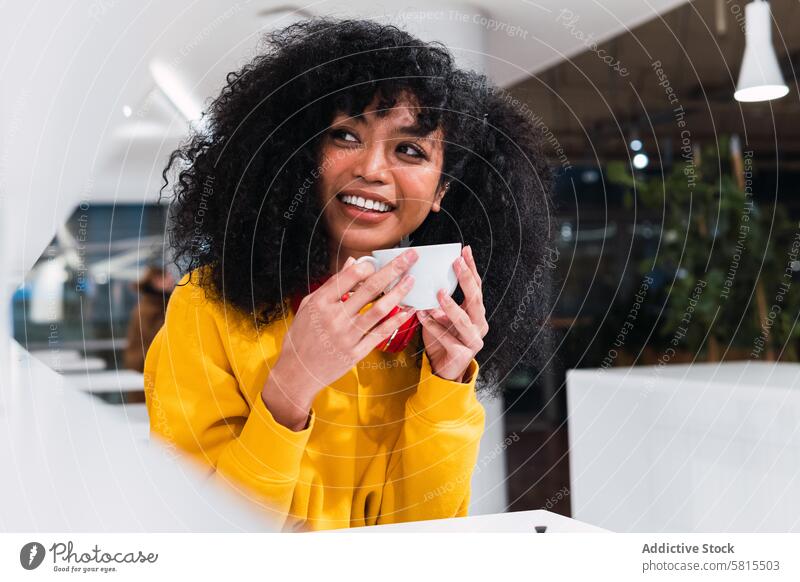 Smiling ethnic woman drinking coffee in cafe smile content cheerful cafeteria style optimist happy female young positive using cup lady glad afro casual
