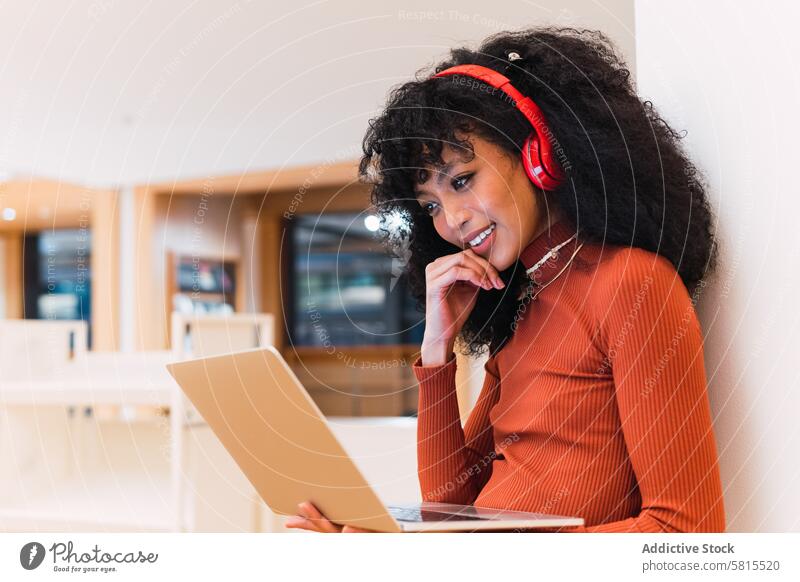 African American lady using laptop and listening to music woman library melomaniac student headphones smile browsing education enjoy ethnic happy