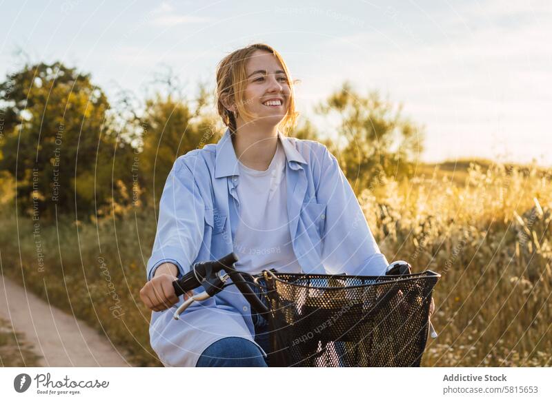 blonde young woman cycling on a field. sunset countryside nature bicycle happy bike spring trip road sky summer girl landscape lifestyle mom portrait