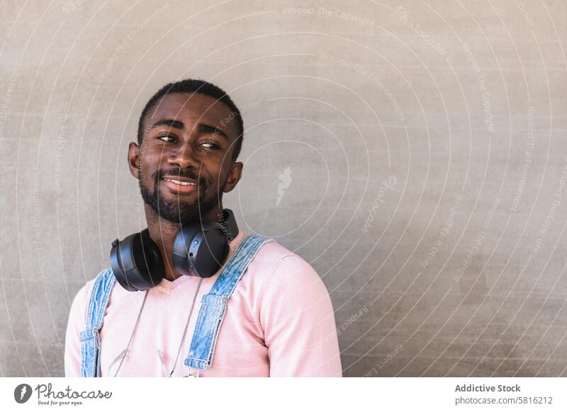 Smiling black man with headphones on street cool city smile appearance trendy outfit wireless cheerful male ethnic african american style happy modern concrete