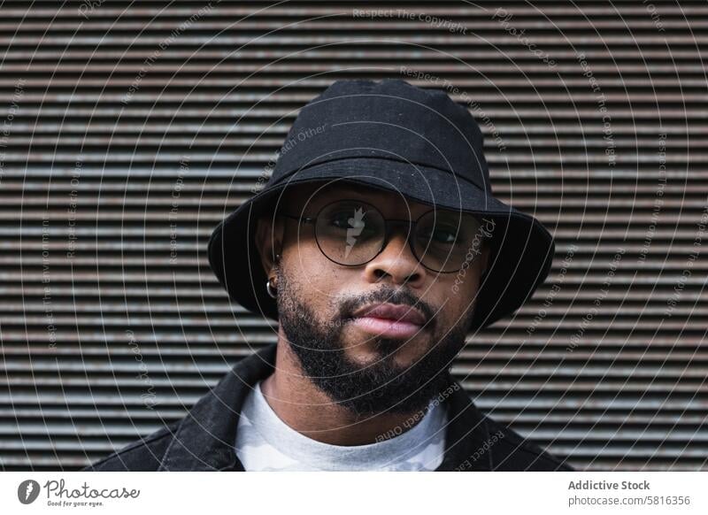 Back hipster man in hat looking at camera trendy smile beard eyeglasses optimist male african american black ethnic outfit style positive joy lifestyle glad