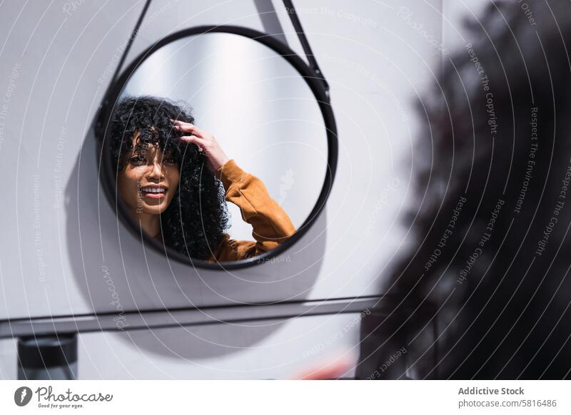 Smiling black woman looking at mirror at home reflection awake morning appearance beauty routine feminine perfect female african american curly hair young