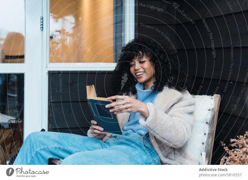 Black woman reading book outside rest relax chill terrace literature story novel female african american black at home weekend smile house free time interest