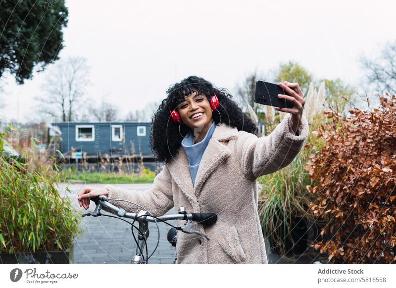 Black woman with smartphone on bicycle taking selfie walk headphones using music listen ride bike chill female african american woman black woman relax city