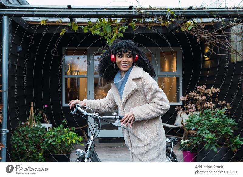 Cheerful black woman in headphones with bicycle using music listen bike chill relax city female african american woman street smile walk stroll positive rest