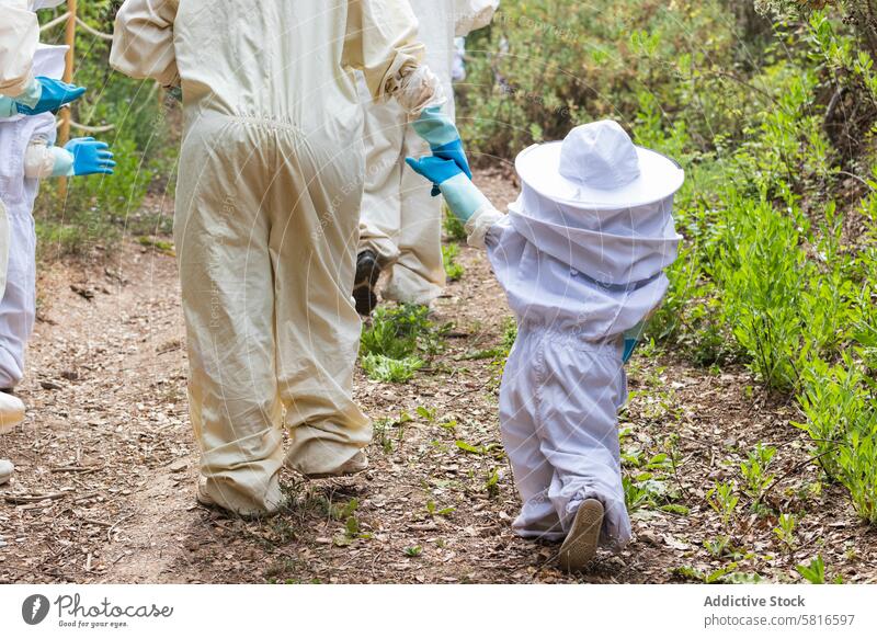 Child and beekeeper holding hands in apiary child costume protect countryside