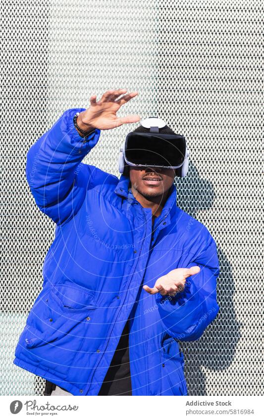 Black man experiencing virtual reality in city goggles vr glasses experience interact touch futuristic male ethnic black african american street metal fence