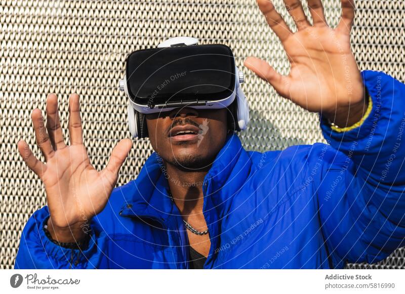 Black man experiencing virtual reality in city goggles vr glasses experience interact touch futuristic male ethnic black african american street metal fence