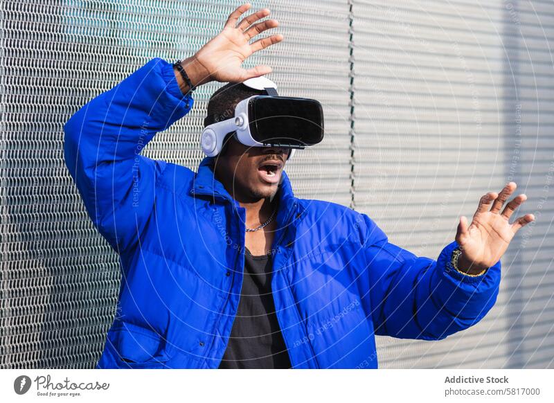 Black man experiencing virtual reality in city goggles vr glasses experience interact touch futuristic male ethnic black african american street metal fence