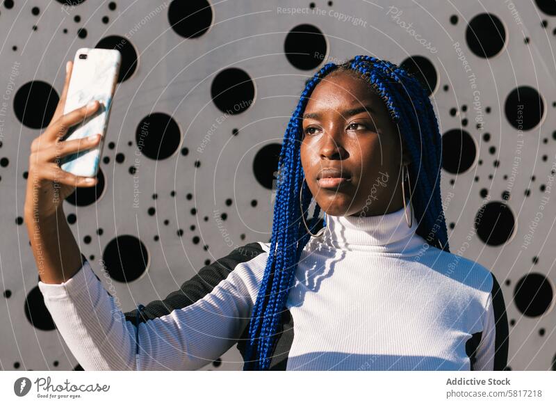 Serious black woman taking selfie on street blue hair braid hairstyle serious trendy color smartphone female ethnic african american environment photo urban