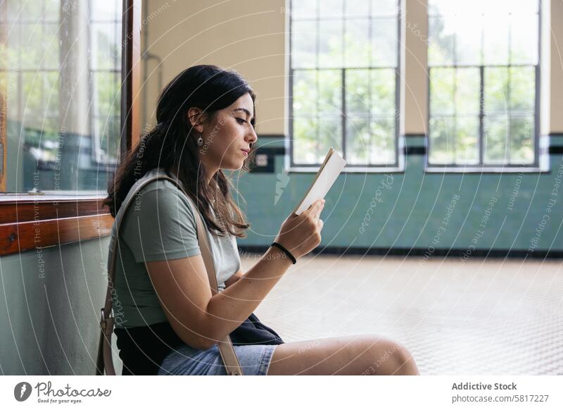 Woman reading a book city concentration expertise famous place indoors literature morning railroad station relaxation sitting sunlight tourism tourist waiting