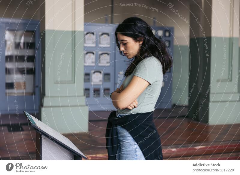 A woman stands reading an informational sign in a museum advice bright focus concept indoors information sign message old railroad station retro style side view