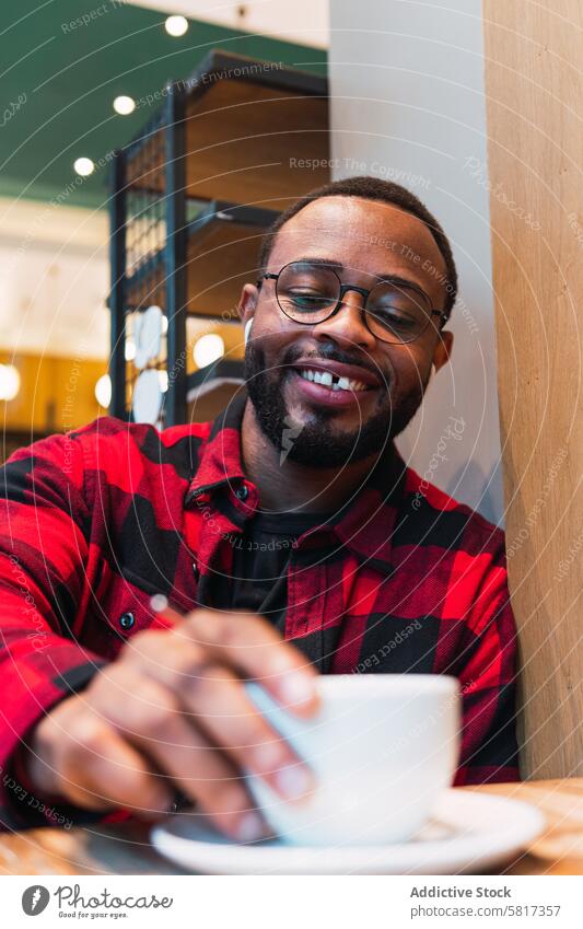 Smiling black man with cup of coffee in cafe earphones using hot drink coffee break music rest relax male african american beverage smile listen enjoy weekend
