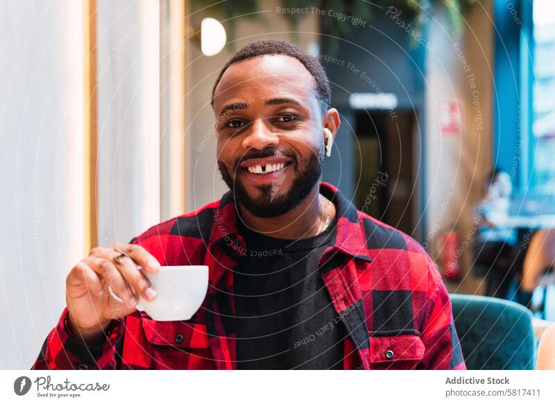 Smiling black man with cup of coffee in cafe earphones using hot drink coffee break music rest relax male african american beverage smile listen enjoy weekend