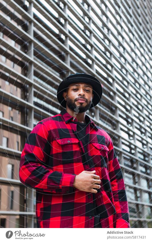 Black man in stylish outfit on street style city appearance individuality personality checkered shirt hat male portrait black african american urban beard