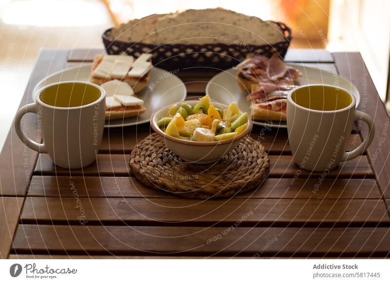 Breakfast in a house with bread, ham, cheese, fruit and coffee on a wood table. breakfast home kitchen food design decor modern interior no people furniture