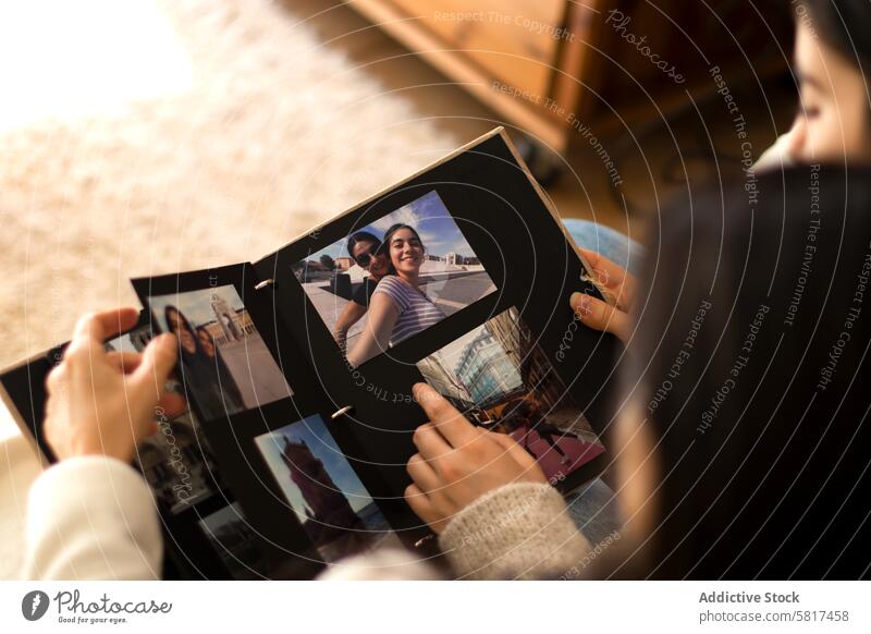 People watching a photo album of themselves people home together woman book relationship happy love sitting young memories female look holding mother overhead