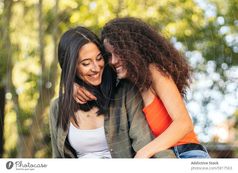 two young women couple sitting hugging in a park woman happy together love people romantic relationship girl female lifestyle casual beautiful smile lovers