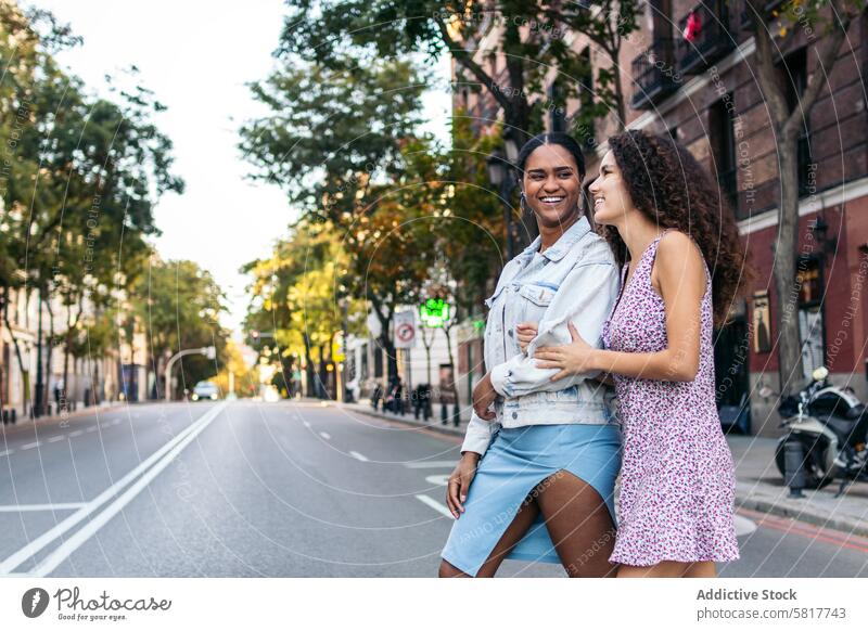 Two girls crossing the pedestrian crossing in the city. two road people street traffic urban casual together walking outdoors day sidewalk friendship careful