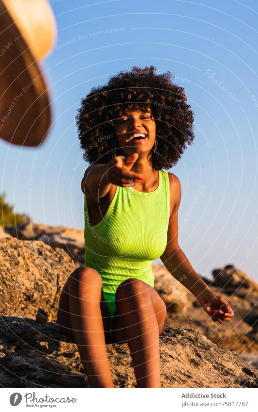 Ethnic woman tossing hat in camera straw hat beach summer vacation having fun cheerful swimsuit female ethnic black african american sunset shore holiday coast