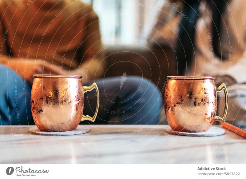 Close up of two vintage style copper mugs for Moscow Mule date cafeteria people sitting restaurant couple happy lifestyle relationship love meeting conversation