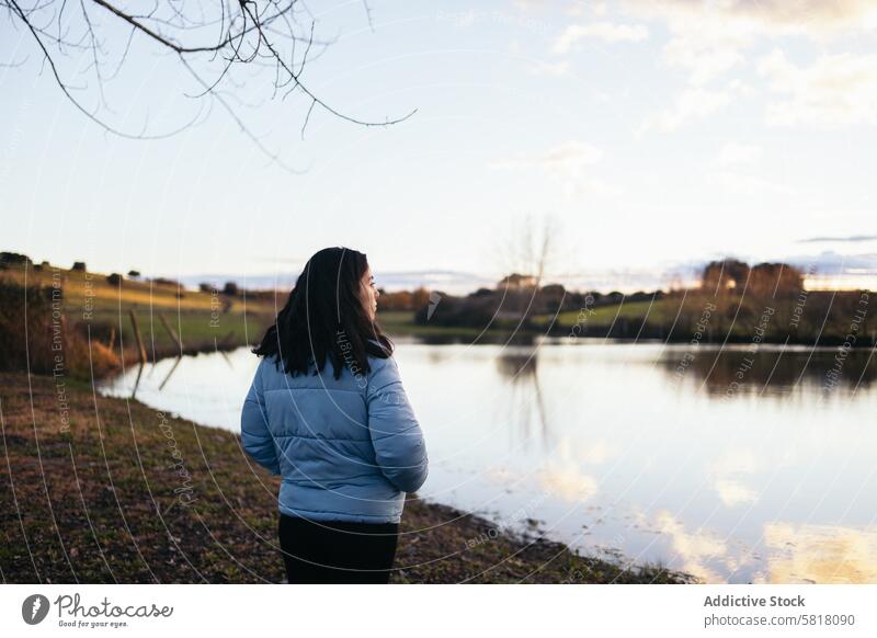 Woman watching the sunset on a lake nature water sky female travel lifestyle landscape view scene outdoors calm peace serene winter cold coat down coat