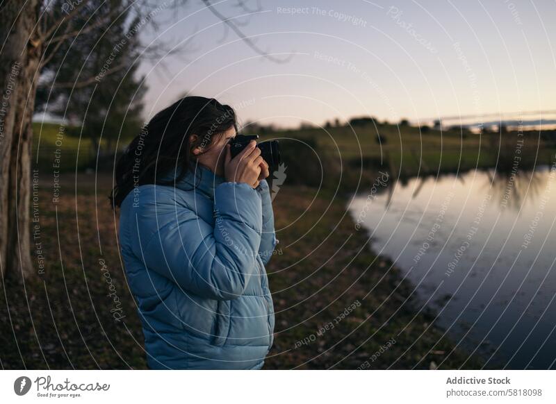 Photographer woman taking photos of a lake at sunset nature water sky female travel lifestyle landscape view scene outdoors calm peace serene winter cold coat