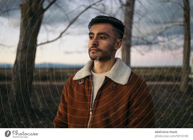 Portrait of an attractive man in nature portrait close up jacket brown beard looking away face expression clothing tree background countryside lifestyle